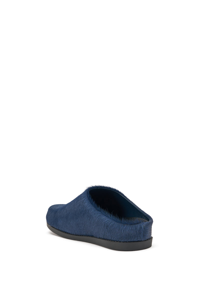 The AZALEA WANG RAMSES NAVY SLIP ON FLAT is a blue mule in genuine calf hair, featuring a fuzzy texture and black sole, displayed from the rear-side against a white background. 5