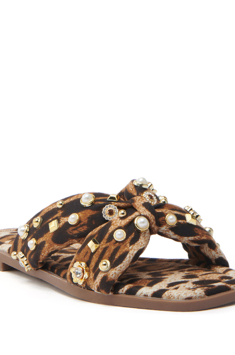 Discover the charm of AKIRA RAMSEY LEOPARD FLAT SANDAL, featuring luxe leopard print, crisscross straps with faux pearls and gold-toned studs. A cushioned insole and flat brown sole complete this chic design, perfect for any fashion-forward ensemble.