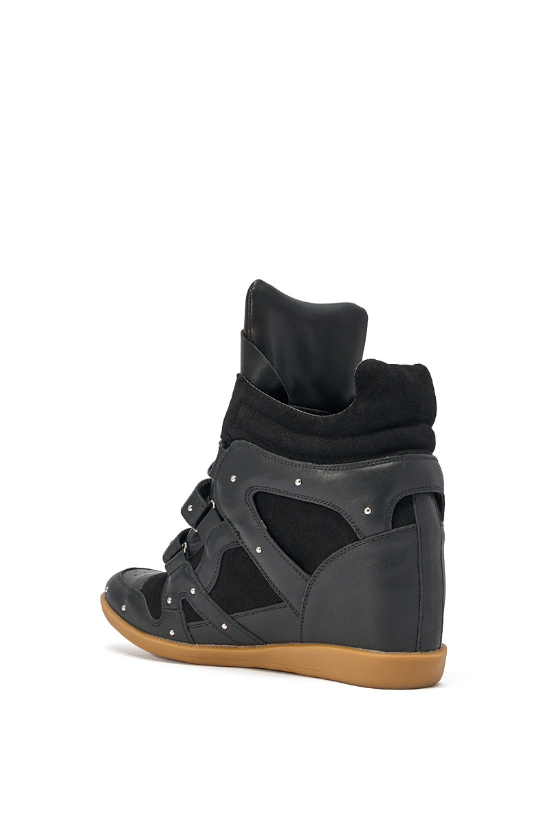 The AKIRA GOLD RANGELEY Black Silver Hardware Embellished Wedge Sneaker features studded faux leather, multiple straps, a hidden wedge, and a thick tan sole, shown from an angled rear view against a white background. 4