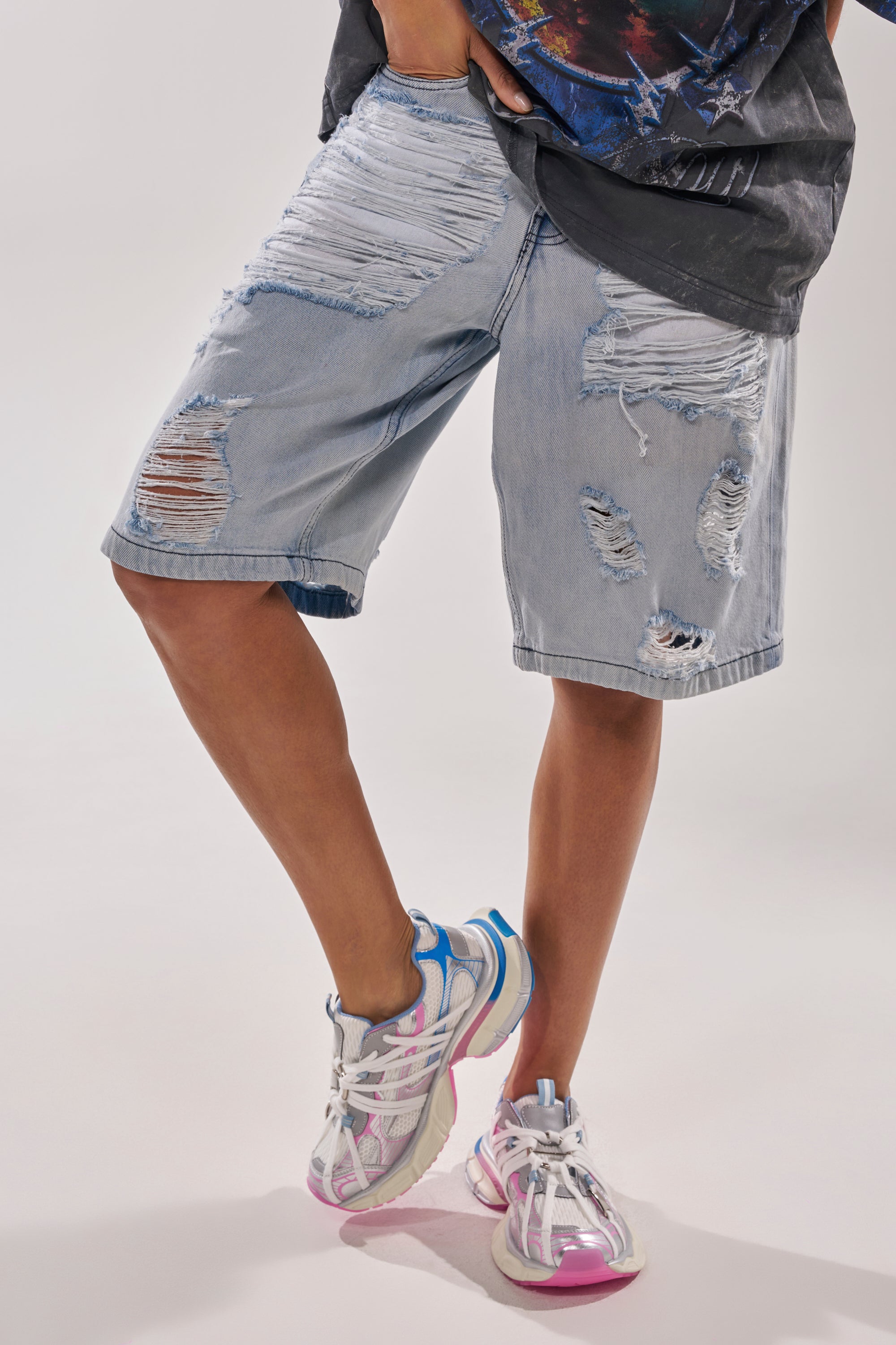 A person in distressed light denim shorts, a dark shirt, and AZALEA WANG RANGLE PINK MULTI LACE SNEAKERS stands with legs crossed against a plain light background. 1