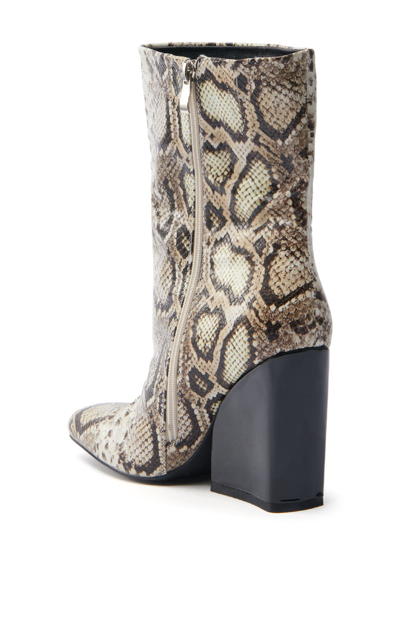 The AZALEA WANG RANSOM BLACK MULTI SNAKE BOOTIE is a vegan leather ankle boot with a snakeskin pattern, featuring a prominent side zipper. The black chunky heel contrasts with the beige and brown reptile print, and the bootie is angled to beautifully showcase its side and back.