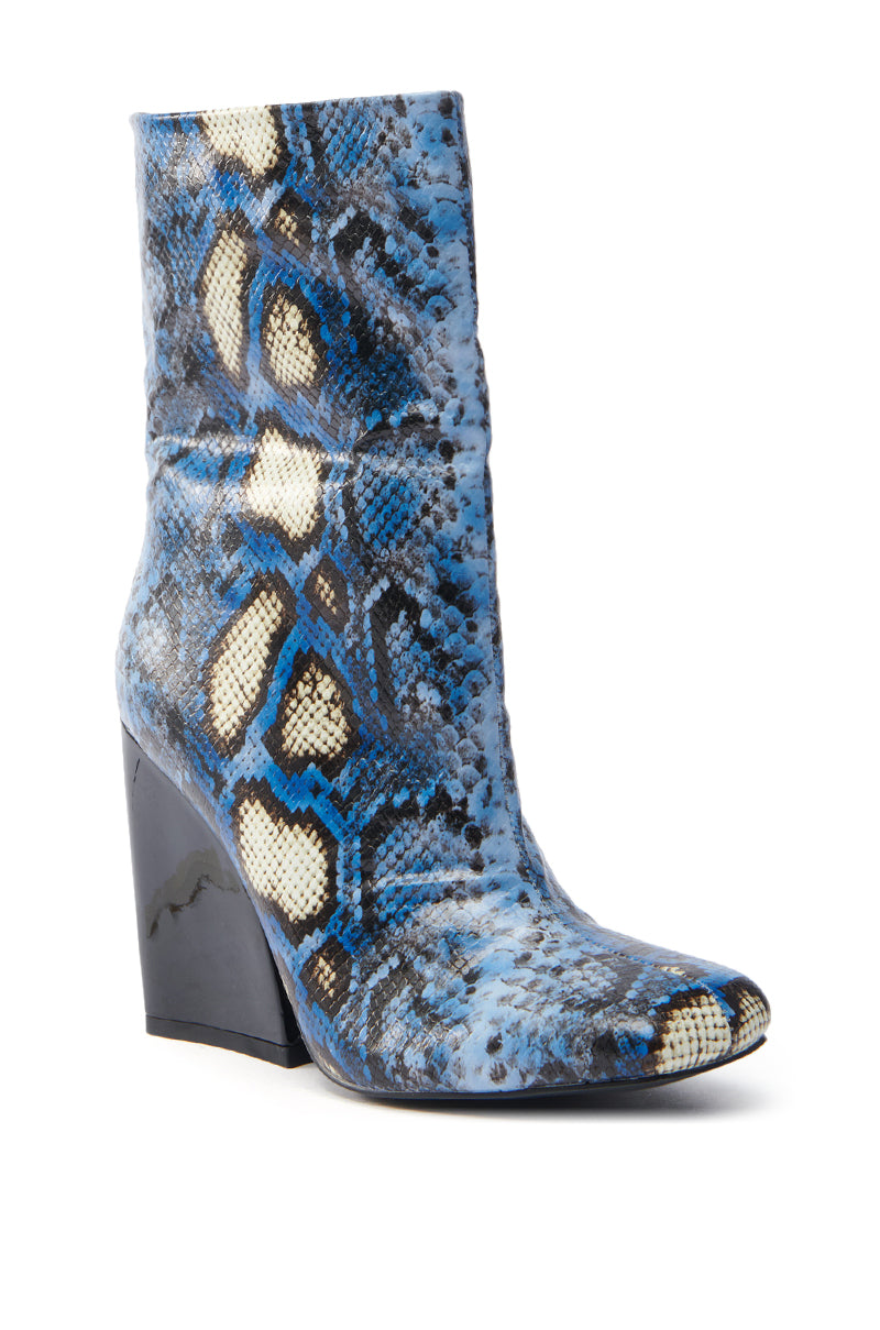 The AZALEA WANG RANSOM BLUE MULTI SNAKE BOOTIE features a vegan leather ankle boot with a faux snakeskin pattern in blue, black, and cream. It sports a pointed toe and chunky, glossy black heel for an edgy look.