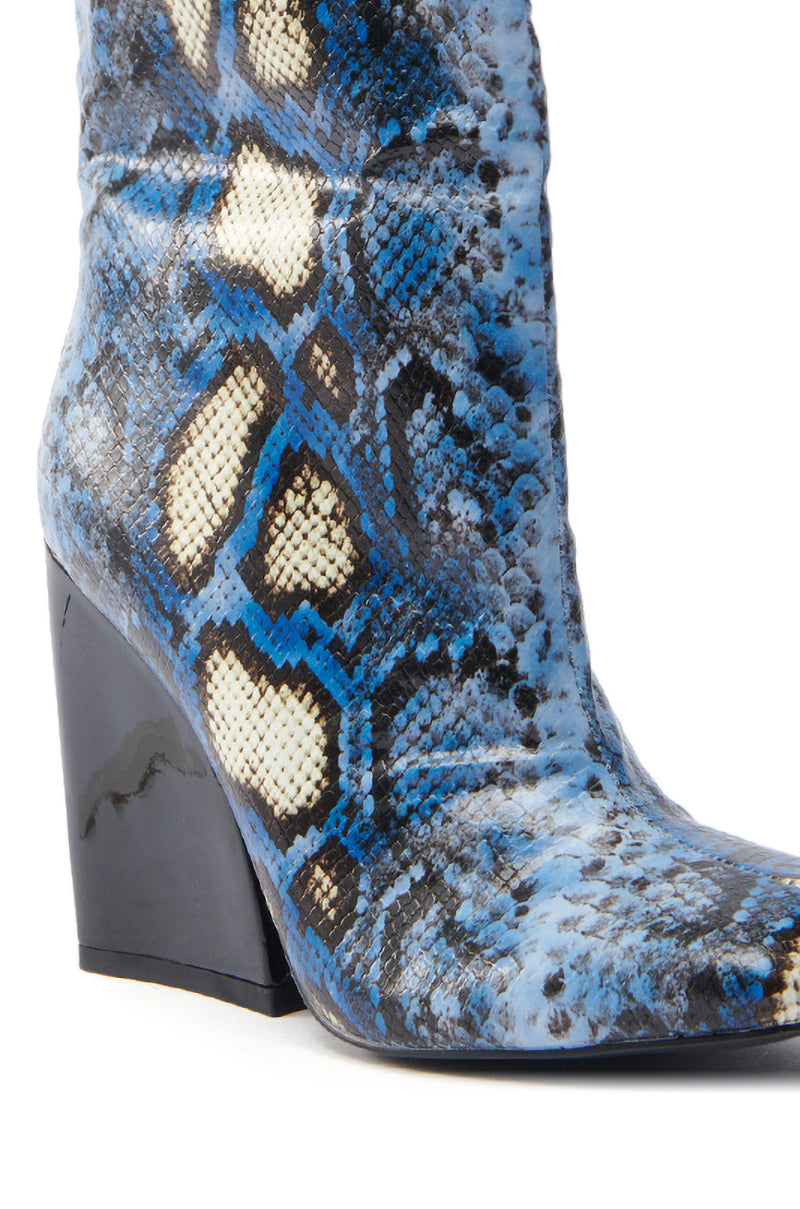 The AZALEA WANG RANSOM BLUE MULTI SNAKE BOOTIE features a close-up of blue, black, and cream vegan leather in a snakeskin pattern with a black chunky angled heel and pointed toe.