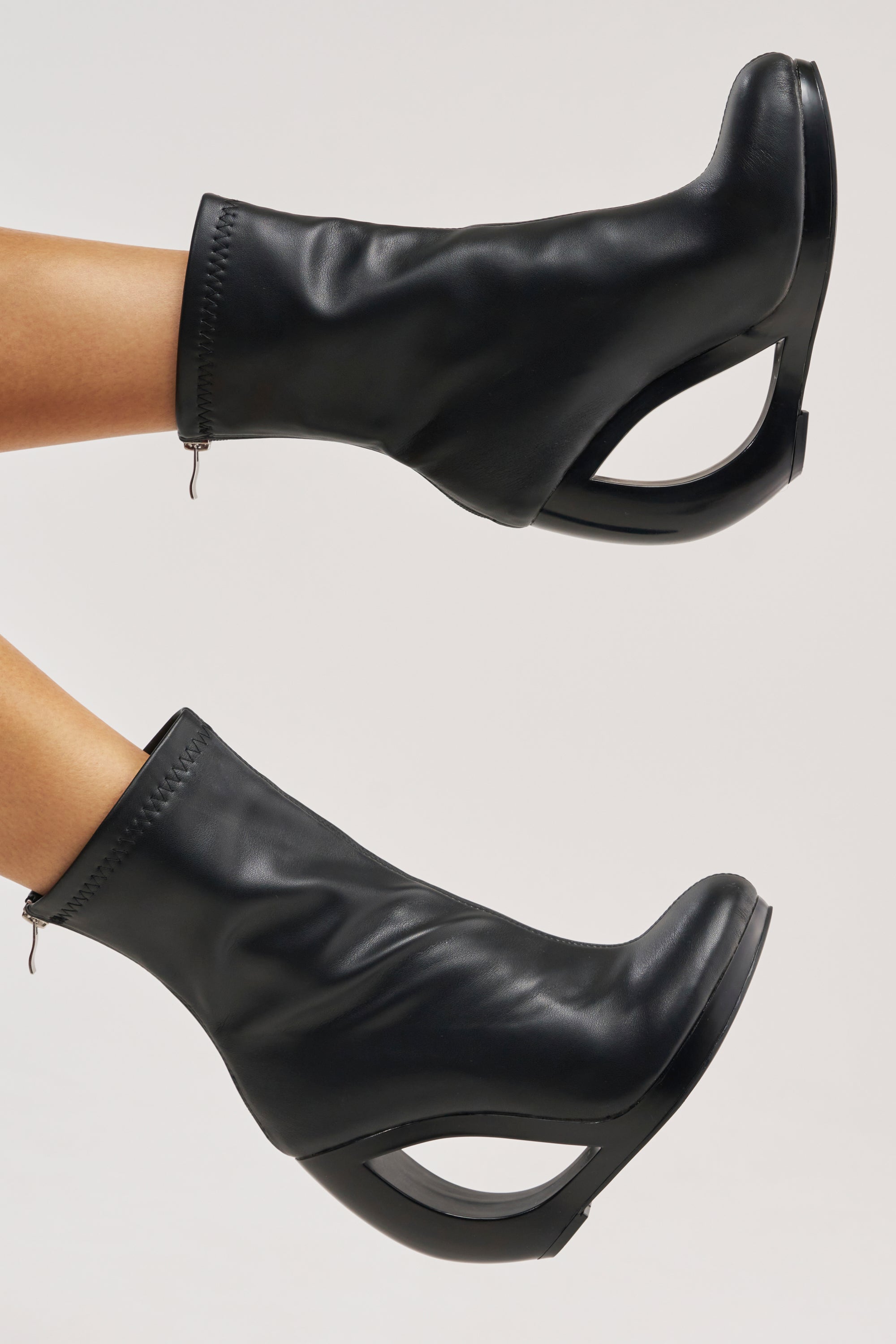 Elevate your date night look with the AZALEA WANG RAPTURE OPEN WEDGE COCKTAIL BOOTIE—black faux leather booties featuring sculptural open-cut wedge heels, perfect for making a bold, stylish statement against any backdrop.