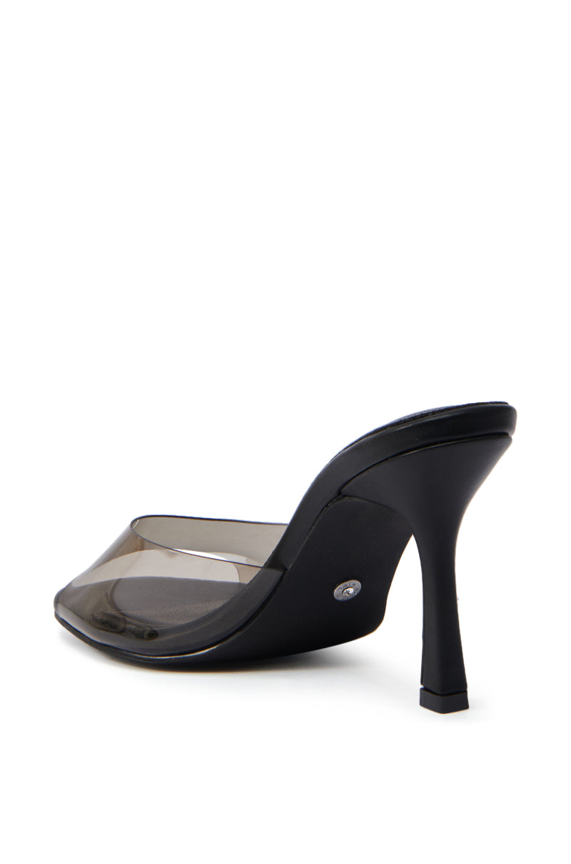 The AKIRA RAYA BLACK PVC CHUNKY HEEL SANDAL features a black mule design with a pointed toe and transparent PVC foot band, shown angled to highlight the side and back of its flared chunky heel against a white background.