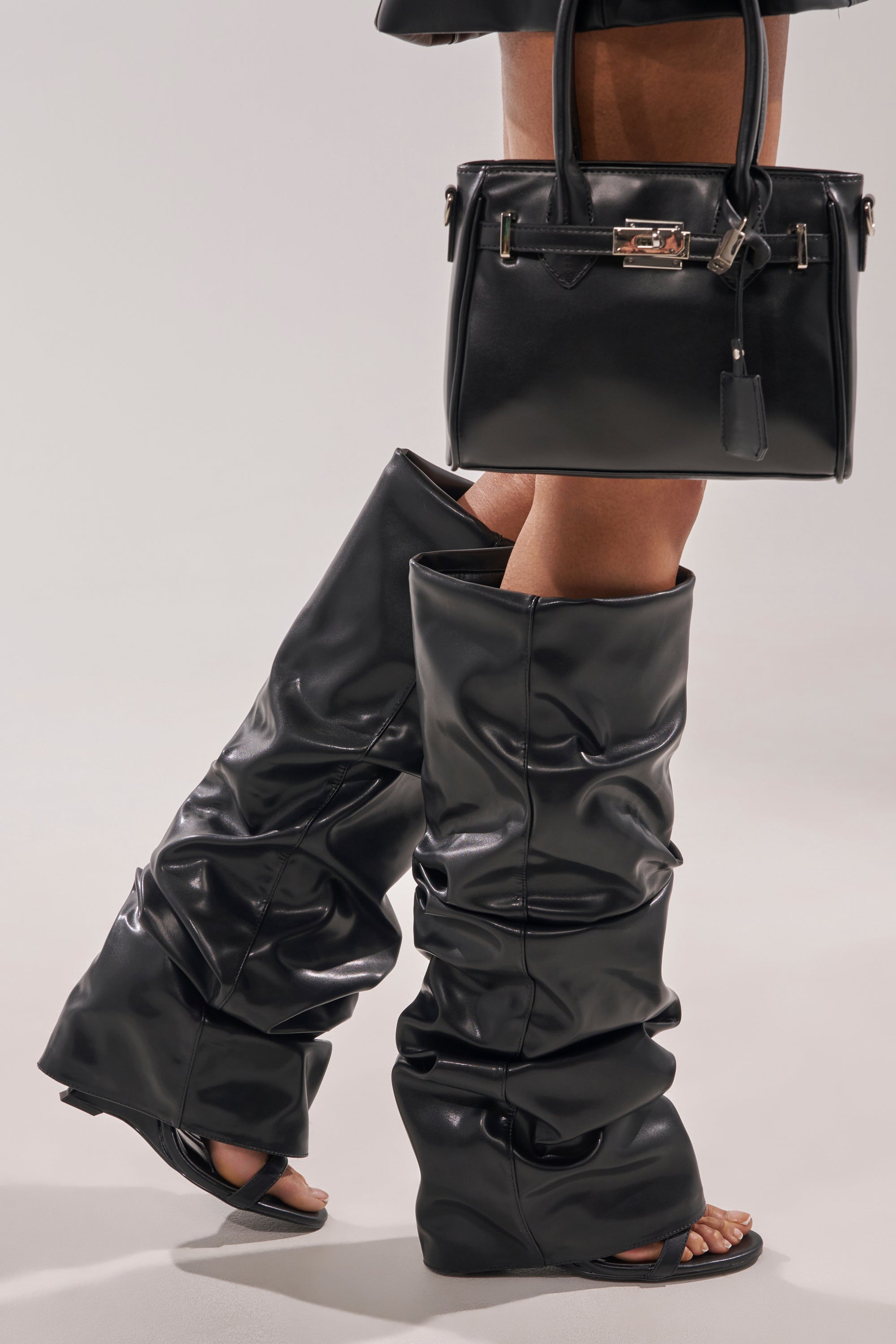 Wearing the AZALEA WANG RAYLAN BLACK GLADIATOR SANDAL with open toes and high heels, paired with a structured black handbag, creates a bold, modern look reminiscent of stylish knee-high gladiator sandals. 0