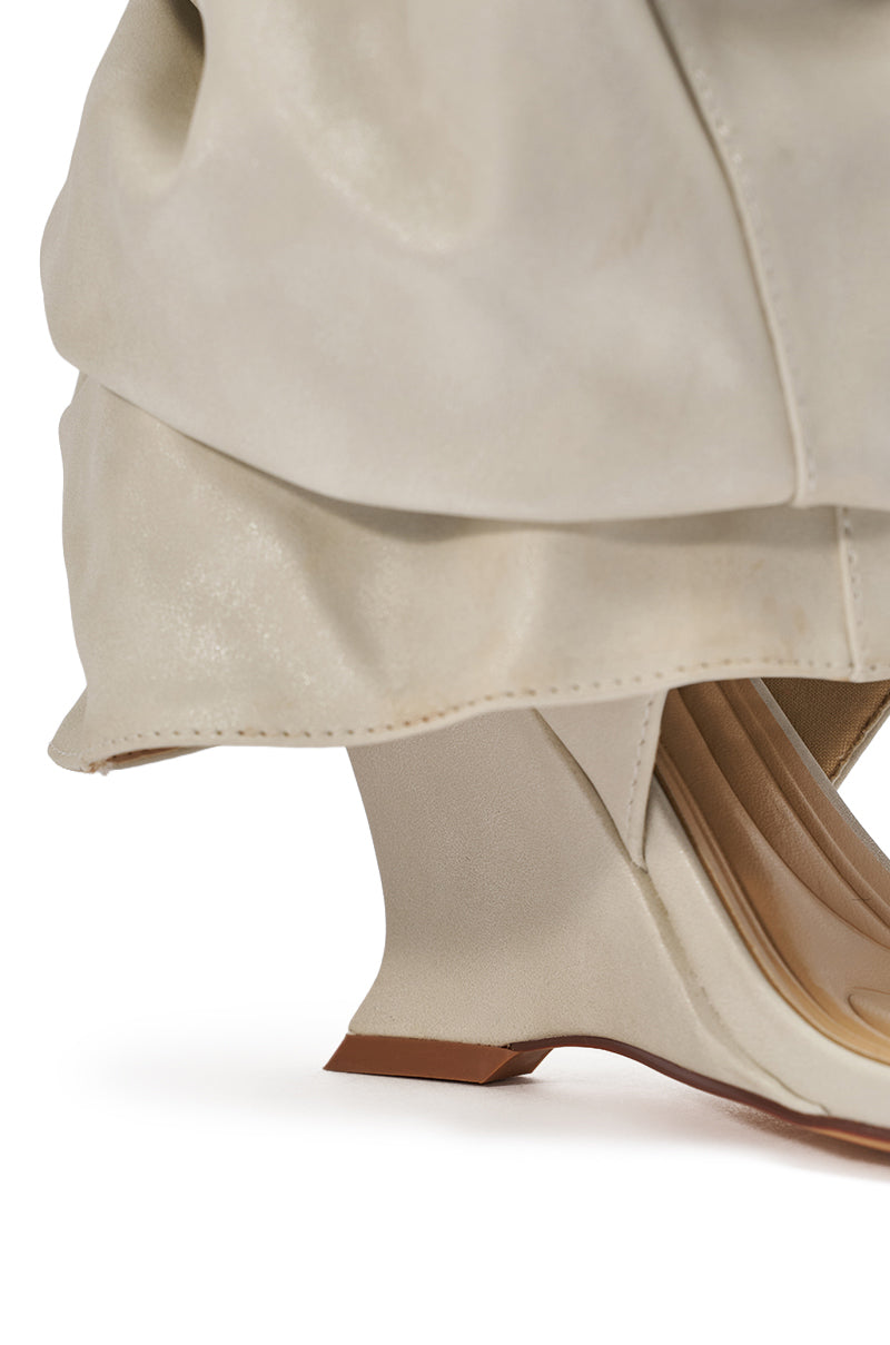 Close-up of the AZALEA WANG RAYLAN BONE GLADIATOR SANDAL, featuring an off-white hue, unique angular heel, ruched soft leather upper reminiscent of slouchy boots, and visible stitching. Displayed on a white surface to highlight its smooth texture. 6