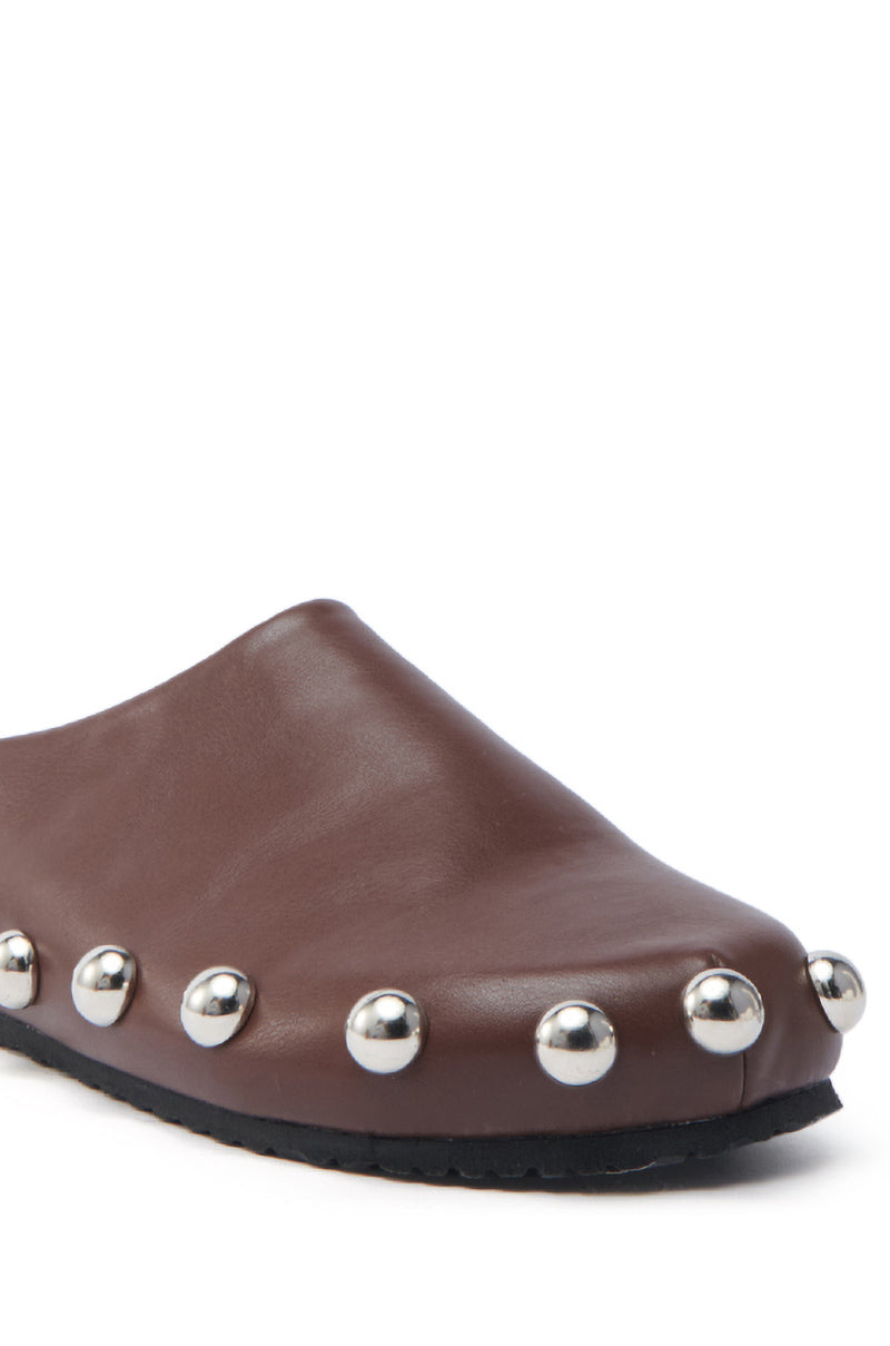 The AZALEA WANG RAYNE BROWN FLAT is a brown slip-on leather shoe with an almond toe, adorned with silver metal studs along the seams, set against a white background.