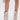 A person wears the AZALEA WANG REEVES NEW OPEN TOE PU BOOTIE IN BONE and carries a small silver wire handbag, with the photo highlighting their legs and accessories against a plain white background.