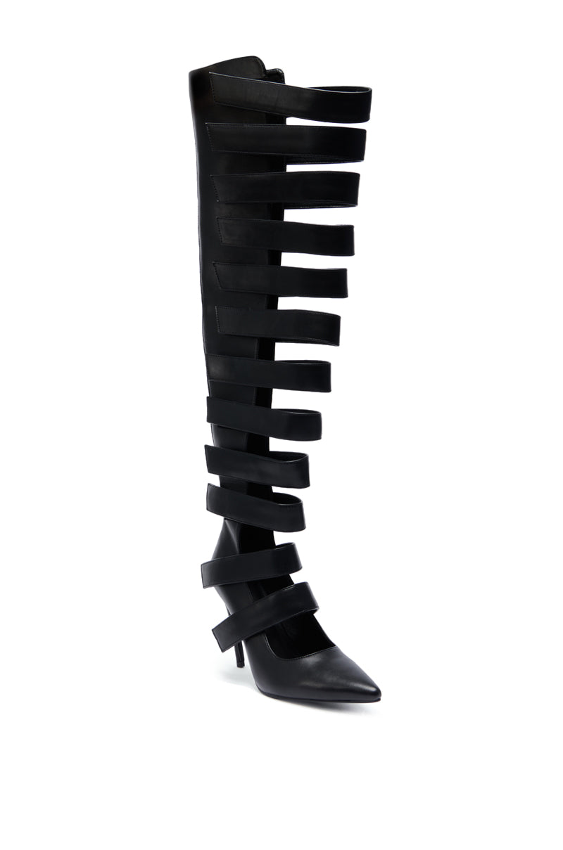 The AZALEA WANG REIN BLACK THIGH HIGH BOOT is a black faux leather boot with multiple wide horizontal straps up to the thigh, creating a cage-like look. It features a pointed toe and a short heel.