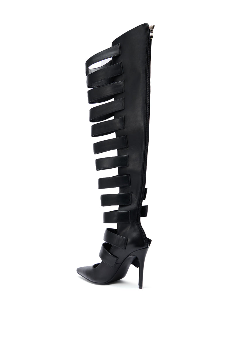 The AZALEA WANG REIN BLACK THIGH HIGH BOOT features faux leather, a high heel, gladiator-inspired cutouts, and wide straps along the shaft; displayed in profile on a white background.