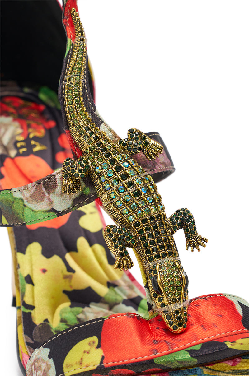 Step out in style with the AKIRA GOLD REPTILIAN MULTISATIN STRAP STILETTO SANDAL, featuring a vibrant tropical print heel and a jeweled gold lizard on the toe strap sparkling with green and blue rhinestones. 8