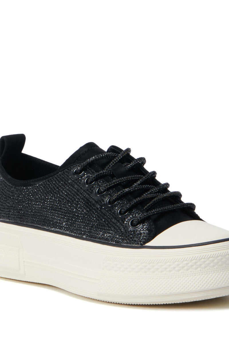A detailed view of the AZALEA WANG REVIVAL BLACK RHINESTONE FLATFORM SNEAKER, showcasing its glittery texture and faux leather upper. This sneaker features a thick, cream-colored flatform sole and black laces, offering a modern and stylish design.