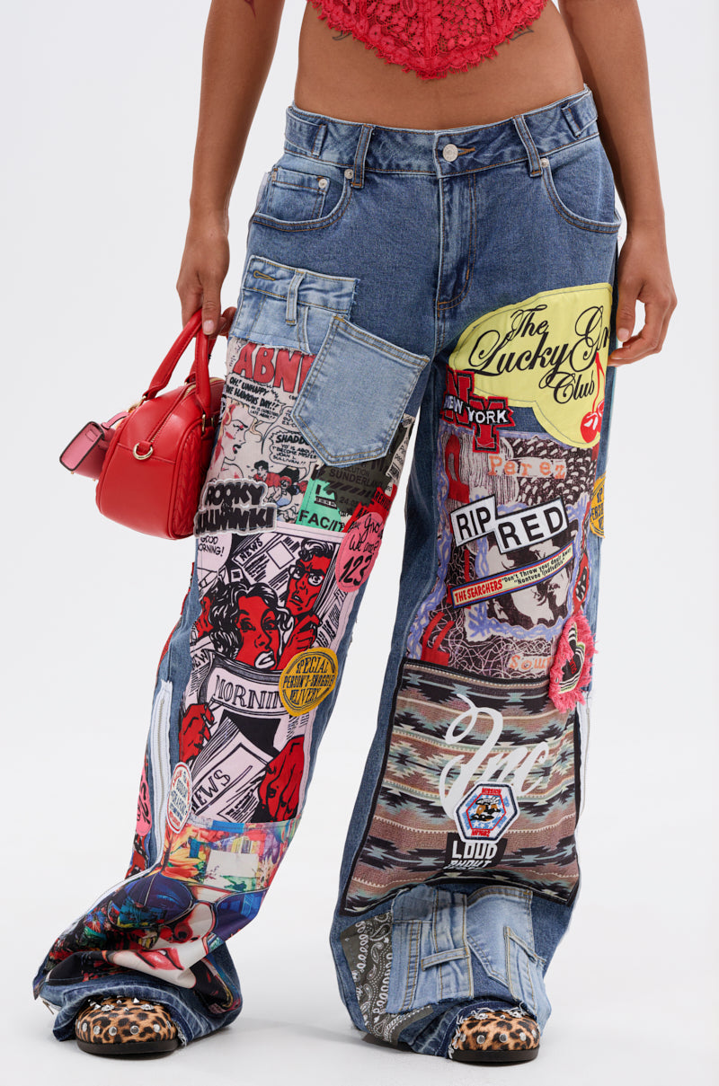 Wearing SO SICK PATCHWORK OVERSIZED JEANS with vibrant graphic patches, styled with a red crop top, red handbag, and animal-print shoes. The background is plain white.