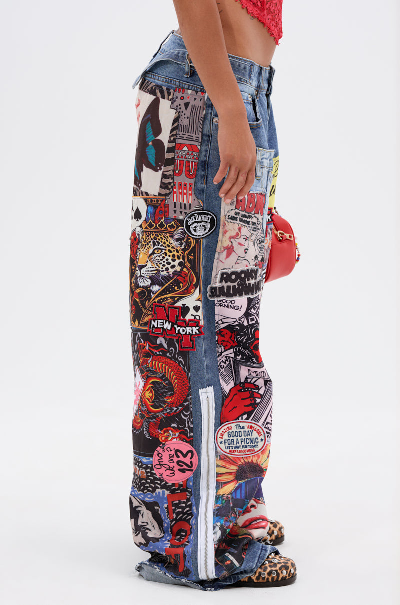 A person stands in profile against a plain white background wearing the SO SICK PATCHWORK OVERSIZED JEANS, which feature colorful comic-style patches and text, styled with a red crop top, small red purse, and leopard print sandals.