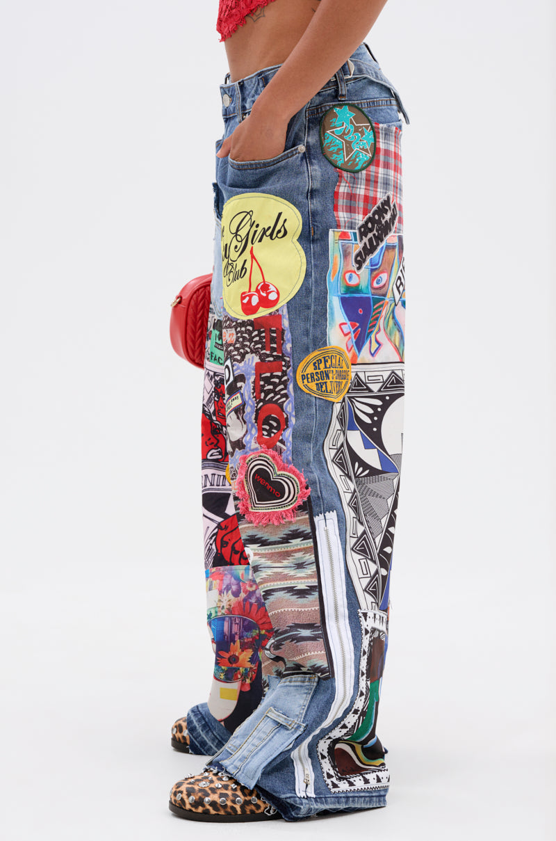 Wearing SO SICK PATCHWORK OVERSIZED JEANS with colorful hearts, cherries, and text graphics, the person pairs them with leopard print shoes and a small red bag. Only the lower body is shown.