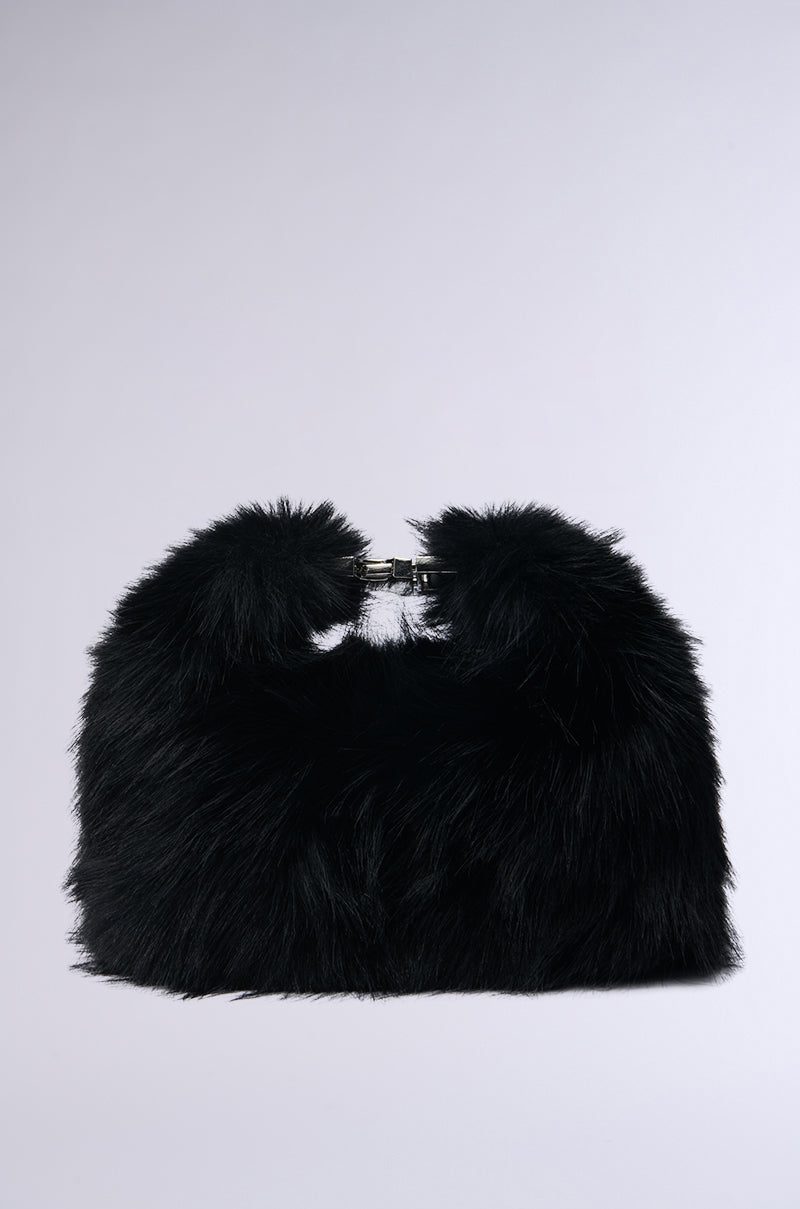 The IM THE ONE MINI FUR PURSE is a black faux fur bag with a soft, fluffy texture. It includes a subtle metal clasp at the top and provides a stylish, modern look with the convenience of a crossbody fit. The background is plain light gray. 0