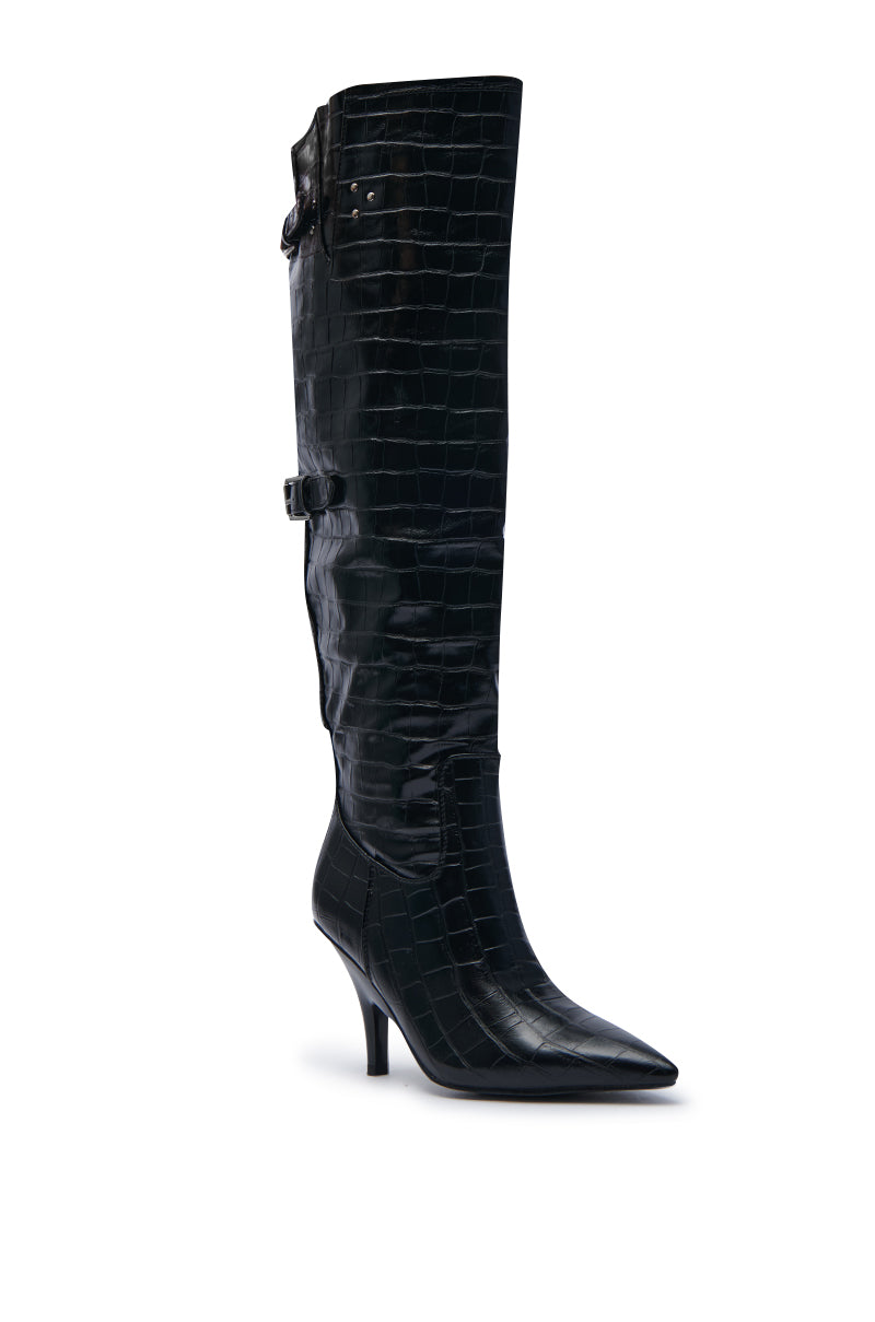 The AZALEA WANG RHODES BLACK CROC WEDGE BOOT is a stylish, black, knee-high boot made from faux crocodile leather, featuring a pointed toe and a mid-height stiletto heel. It has decorative straps with buckles that wrap around the calf, set against a plain white background.