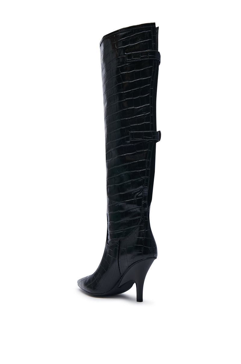 The AZALEA WANG RHODES BLACK CROC WEDGE BOOT is a tall, black leather boot made from faux crocodile material. It features a pointed toe and a wedge stiletto heel for enhanced stability, with side detailing. The boot extends just below the knee, providing both style and elegance.