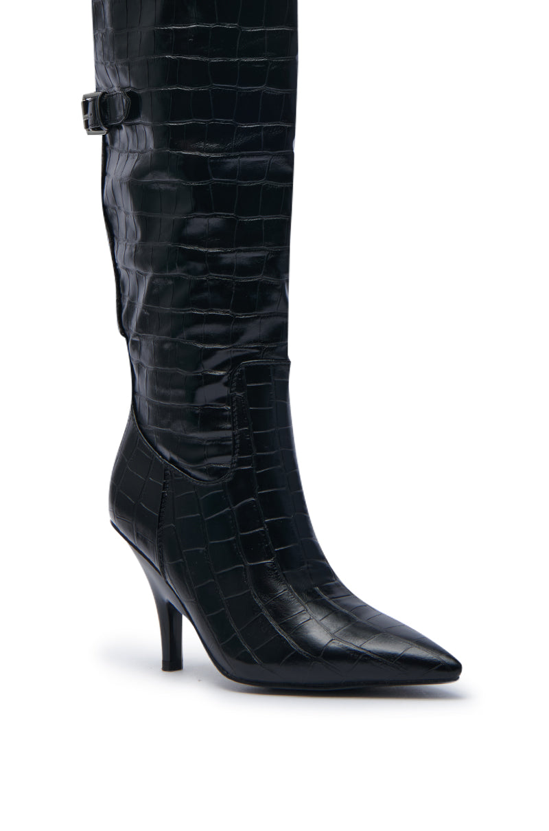 The AZALEA WANG RHODES BLACK CROC WEDGE BOOT is a knee-high boot made from black faux crocodile leather, featuring a pointed toe and a slender wedge stiletto heel. It includes a subtle buckle strap detail near the top of the shaft for a stylish and textured appearance.