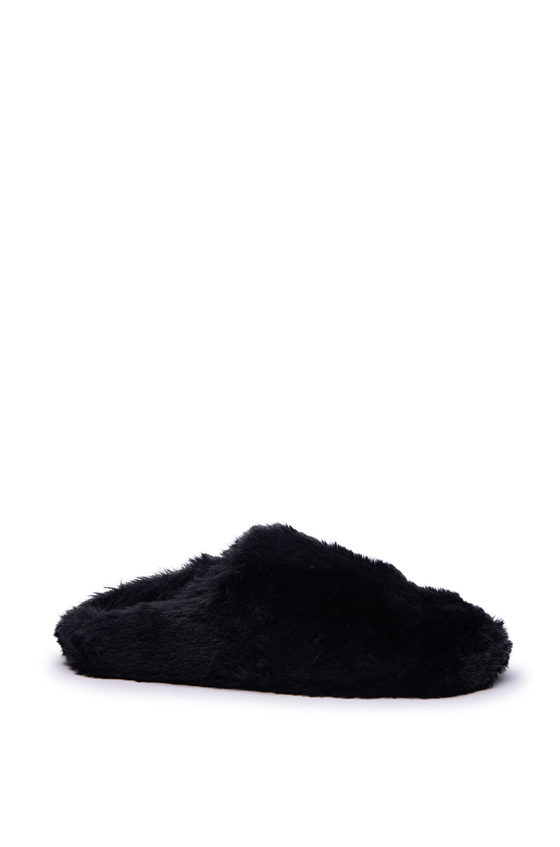 The AKIRA RHYS BLACK FUZZY FLAT is shown from the side, featuring a black faux fur upper, closed toe, open back, and flat rubber sole against a plain white background.