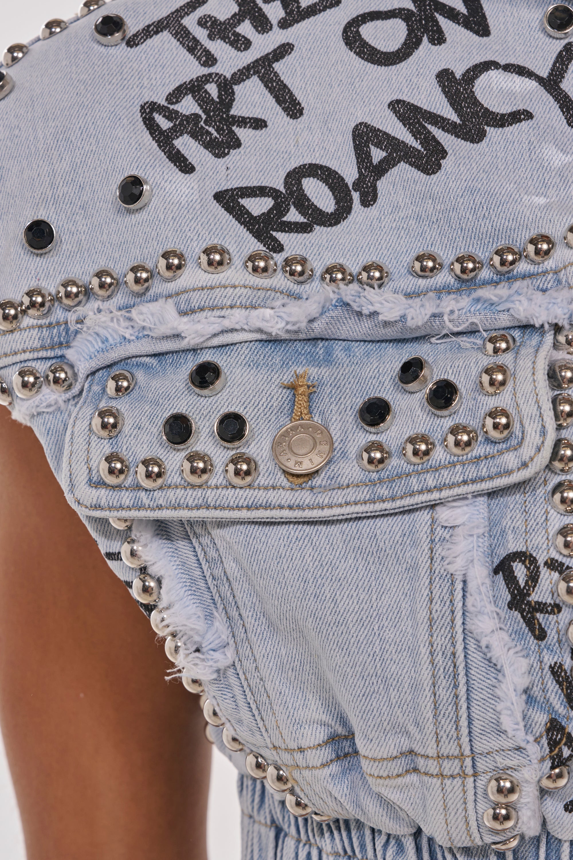 Close-up of the GET INTO THE RHYTHM CROP HOODIE, featuring frayed edges, silver studs, a decorative pin, and bold graffiti-style graphics on the shoulder and pocket—perfect for street-chic layering. 6