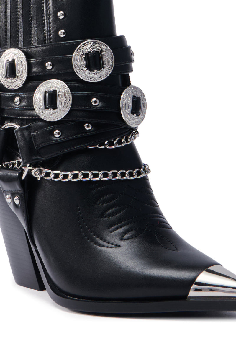 Close-up of the AZALEA WANG RIGGINS black bootie with intricate stitching, silver buckles, chains, hardware, stacked heel, chrome toe cap, and detailed vegan leather design.