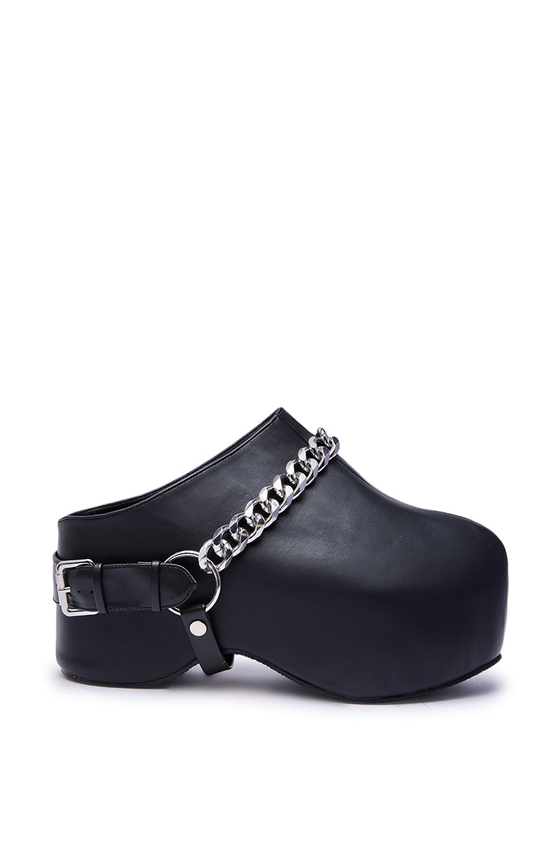 The AZALEA WANG RILLMEY BLACK FLAT CLOG WITH METAL DETAIL features black faux leather, a flat thick sole, silver chain accent on the upper, and an adjustable buckle heel strap.