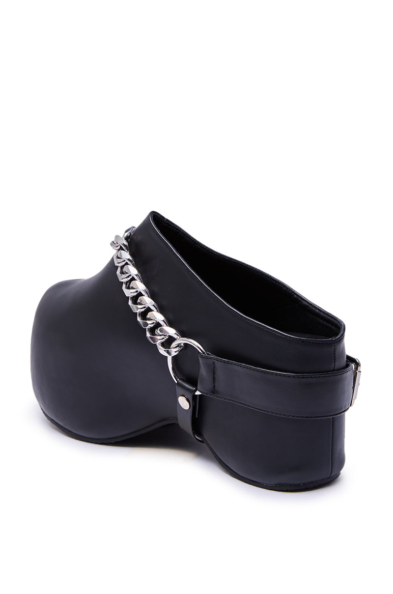 The AZALEA WANG RILLMEY BLACK FLAT CLOG WITH METAL DETAIL is a black faux leather flat clog, featuring a thick sole, silver chain accent across the top, and an adjustable back strap.
