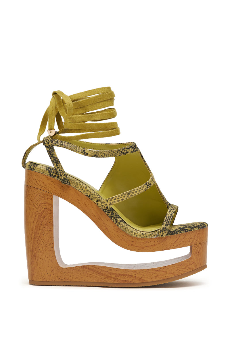 The AKIRA GOLD RIN GREENSNAKE NOVELTY LACE UP WEDGE SANDAL features yellow-green snakeskin straps, sparkly faux leather details, and a distinctive wooden wedge heel with a bold cutout design. 5