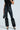 Dressed in black, they wear the RIO FAUX LEATHER LEGGING WITH FUR TRIM and a furry top, complementing their look with studded high heels and a spiked black handbag against a light background. Arms and lower body are visible.