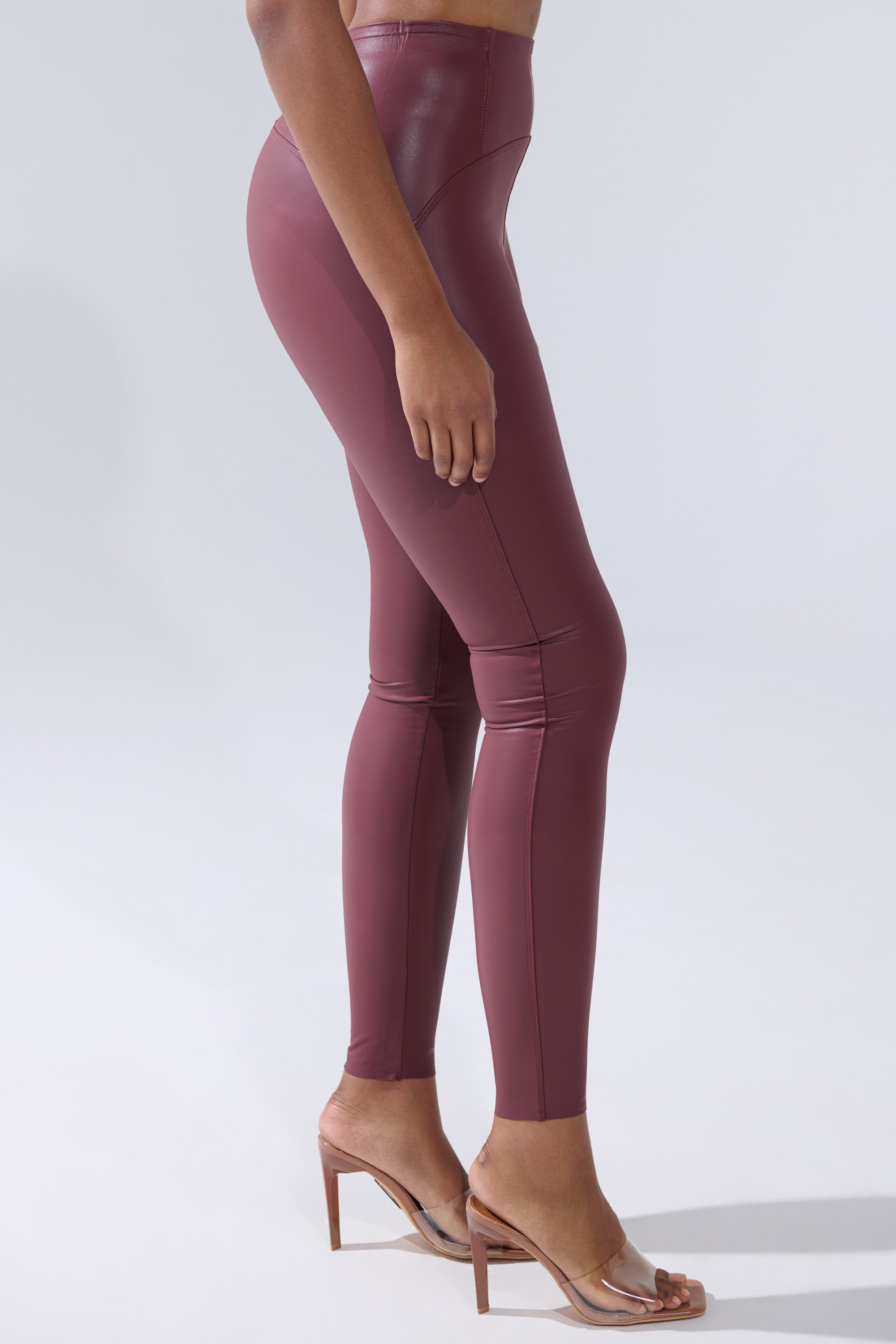 A person wearing the RIO High Rise Legging with 4 Way Stretch in Oxblood and clear heeled sandals, standing sideways against a plain light gray background.