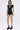 A woman in the LAUREN SEAMLESS ROMPER WITH LACE, featuring a deep V-neck and stretchy fabric, pairs it with black platform heels and sunglasses while posing against a plain white background.