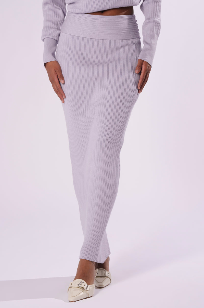 A person is wearing the AKIRA Label CAN'T LOSE SWEATER KNIT MIDI SKIRT in light lavender, which is ankle-length and matches their long-sleeve top. The skirt offers a stylish bodycon fit. They are also wearing light-colored loafers. The background is plain white. 1