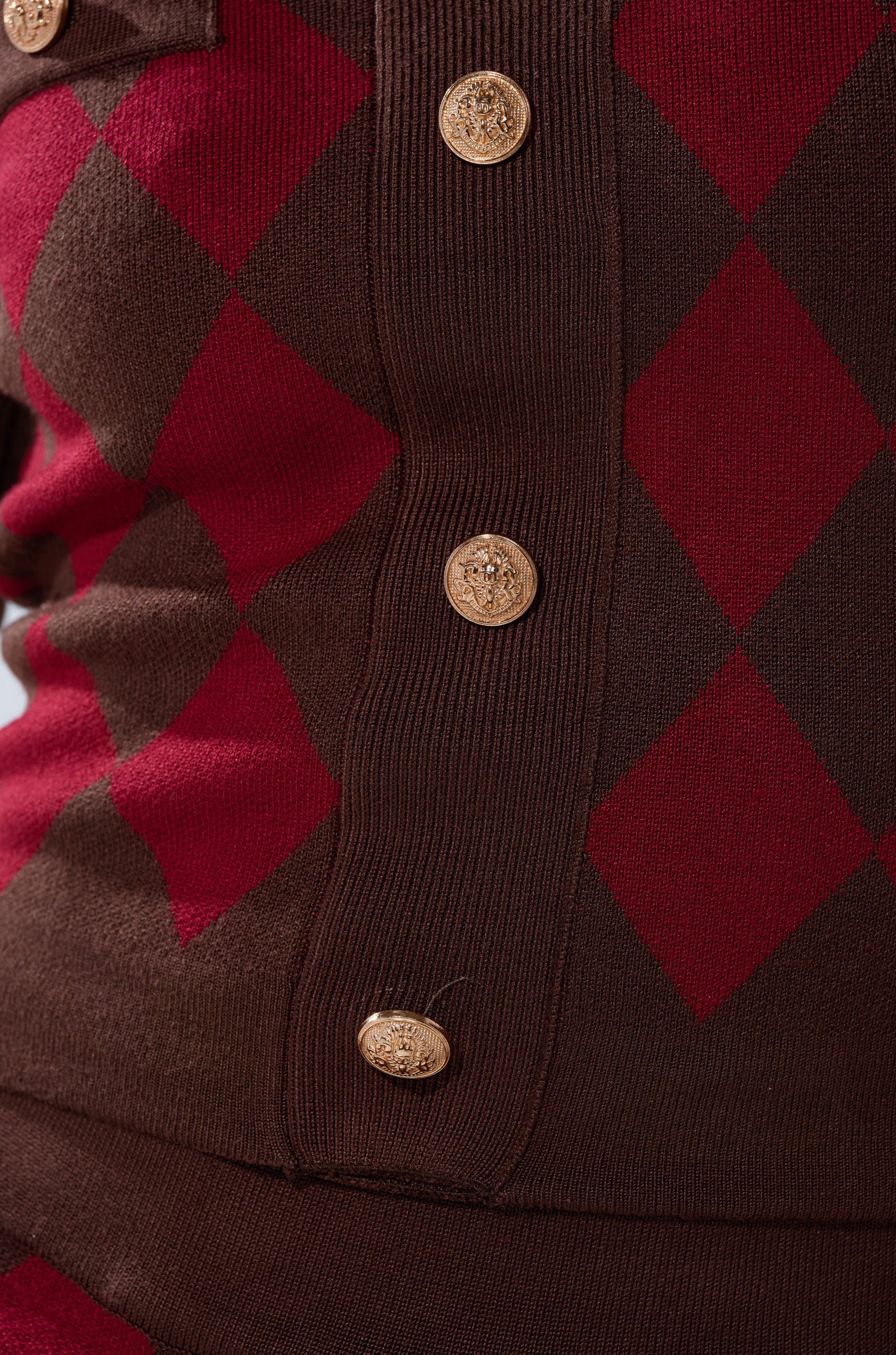 Close-up of THE BEST PART OF THIS ABSTRACT CARDIGAN, a brown and red argyle print sweater with a vertical row of gold embossed buttons and a cropped fit.