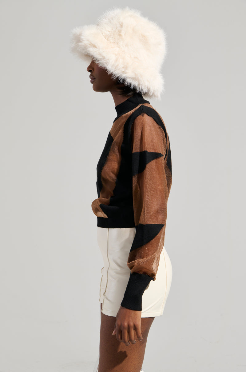 A person wearing a fluffy white hat, the BABY PLEASE MESH PANEL BLACK AND WHITE TOP featuring an abstract colorblock pattern with sheer mesh panels, and white high-waisted shorts. They stand in profile against a light gray background.