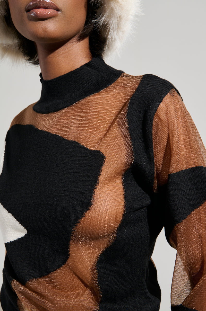A person wearing the BABY PLEASE MESH PANEL BLACK AND WHITE TOP, which features an abstract colorblock pattern and a light-colored fur hat, is shown from the shoulders up against a neutral background, their lips slightly parted.