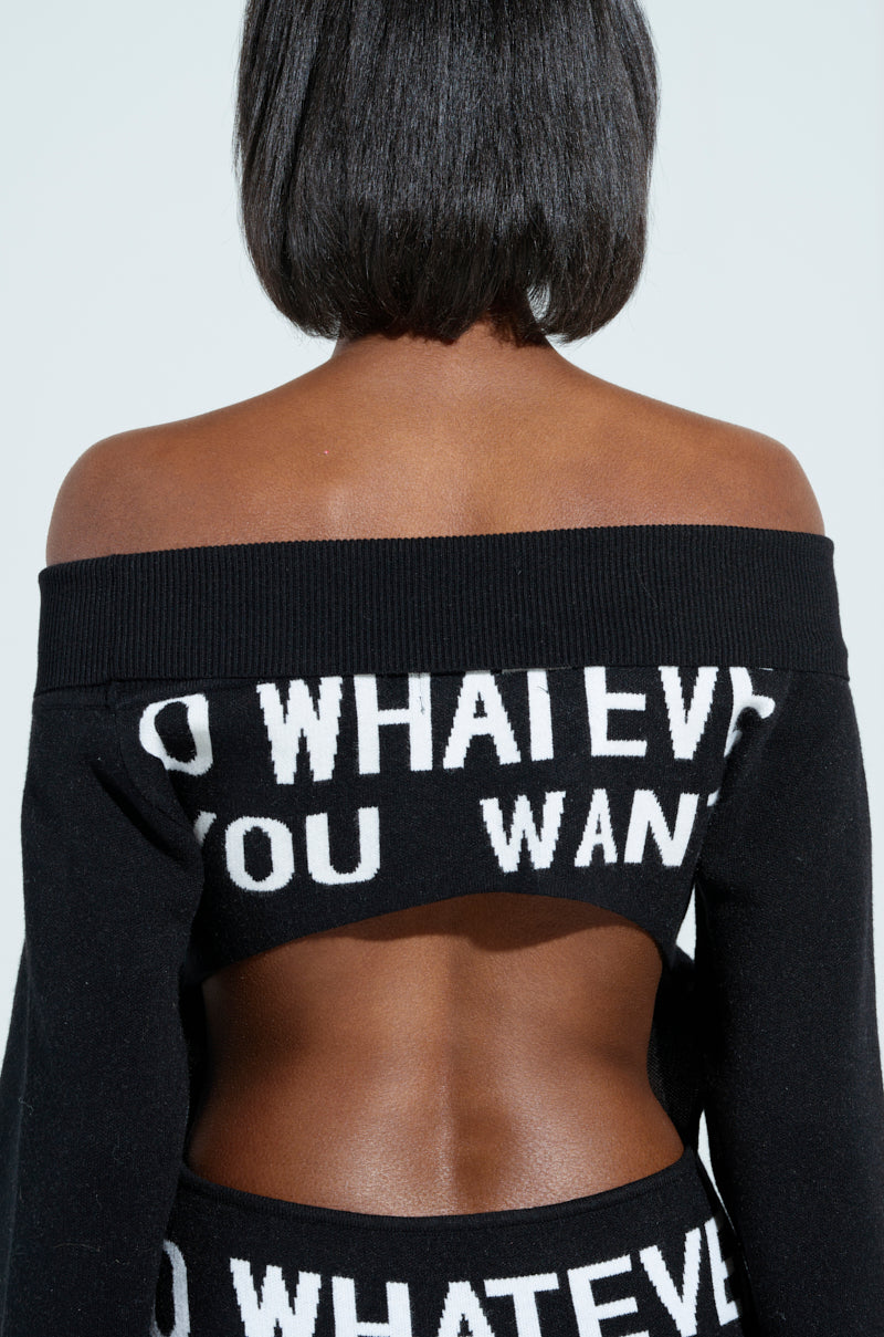 A person with short hair wears the WHATEVER YOU WANT KNIT MAXI DRESS, showcasing an off-the-shoulder, curve-hugging silhouette. The back features cut-out details displaying "DO WHATEVER YOU WANT" in white letters.