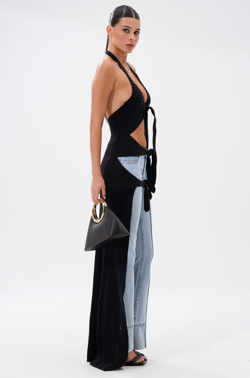 A woman stands sideways in the TIED TO YOU TIE-FRONT SWEATER over two-tone denim jeans, holding a black handbag with a gold handle and wearing black sandals. Her straight dark hair is pulled back.