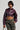 Sporting a shiny Natalia Crocodile PU Button Down Shirt alongside camouflage pants, the person poses confidently. Their short hair and the chain strap they hold accentuate their bold fashion choice against the plain background.