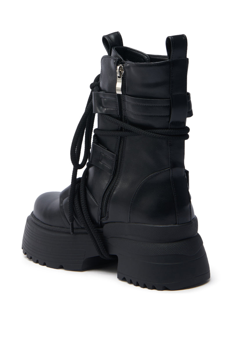 The AZALEA WANG ROISIN BLACK COMBAT BOOTIE is a black vegan leather bootie with a chunky heel, thick black laces, side zipper, strap details, and a textured sole for excellent grip, offering a rugged yet stylish appearance.