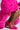 A person crouches in a vibrant pink faux fur coat and AZALEA WANG ROMEE fuchsia pony hair pumps. The pointed toe and stiletto heel add sophistication to the ensemble, creating a bold, fashion-forward look against a plain background.