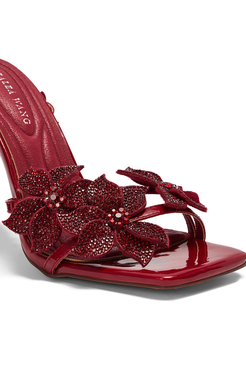 The AZALEA WANG ROMI DARK CHERRY RHINESTONE FLORAL EMBELLISHED SANDAL features glossy faux patent leather, red floral decorations, and sparkling rhinestones on the stiletto straps.