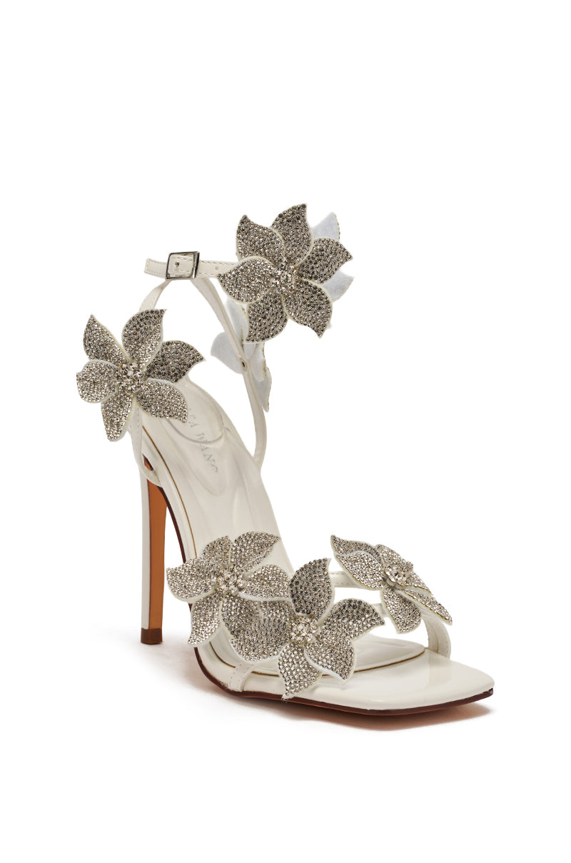 The AZALEA WANG ROMI WHITE FLORAL WITH RHINESTONES STILETTO SANDAL features a white faux patent leather base, slender stiletto heel, thin ankle strap, open toe, and large silver rhinestone-embellished floral accents.