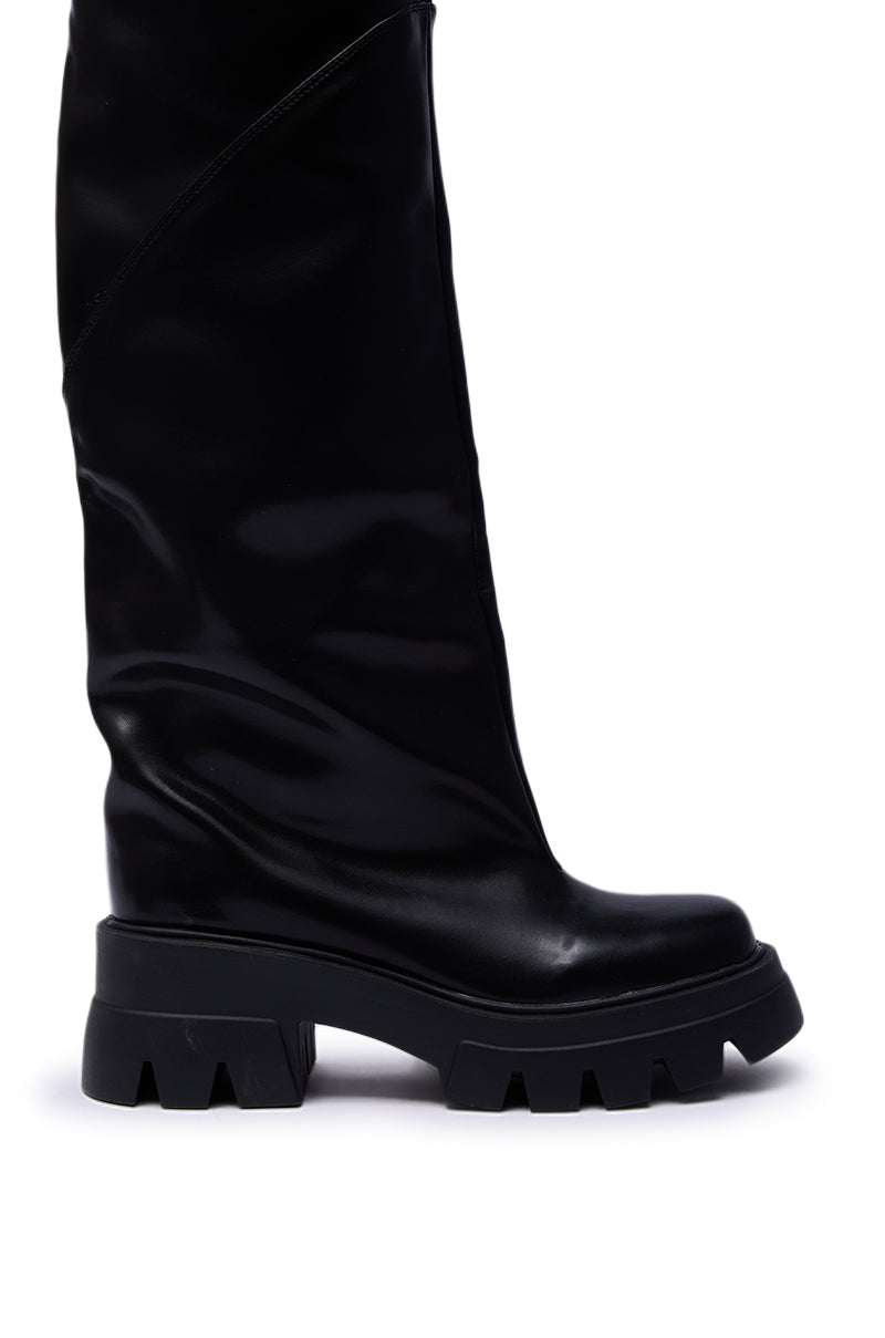 The AZALEA WANG RONAN BLACK SLOUCH BOOT features tall black faux leather, chunky ridged soles, and a slightly slouchy shaft, shown from the side against a white background.
