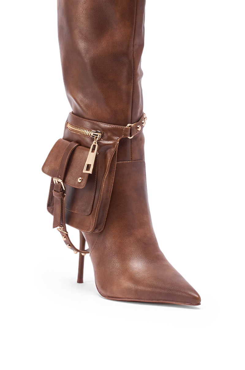 The AZALEA WANG RONDEL BROWN DISTRESSED STILETTO BOOT is a brown knee-high leather boot with a pointed toe, high stiletto heel, gold hardware, and a zippered pocket with a flap.
