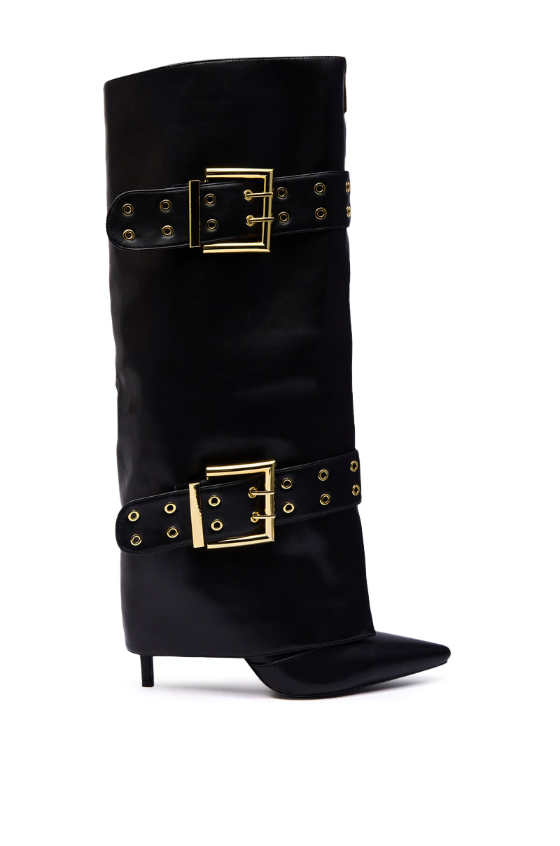 The AZALEA WANG ROOVER Black Hardware Embellished Stiletto Boot is a black faux leather knee-high boot with a pointed toe, thin heel, and two wide straps adorned with large gold buckles and grommets on the shaft.