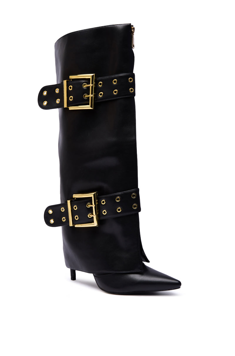 The AZALEA WANG ROOVER BLACK HARDWARE EMBELLISHED STILETTO BOOT is a black knee-high faux leather boot with a pointed toe, stiletto heel, and two wide straps detailed with large gold buckles and grommets.
