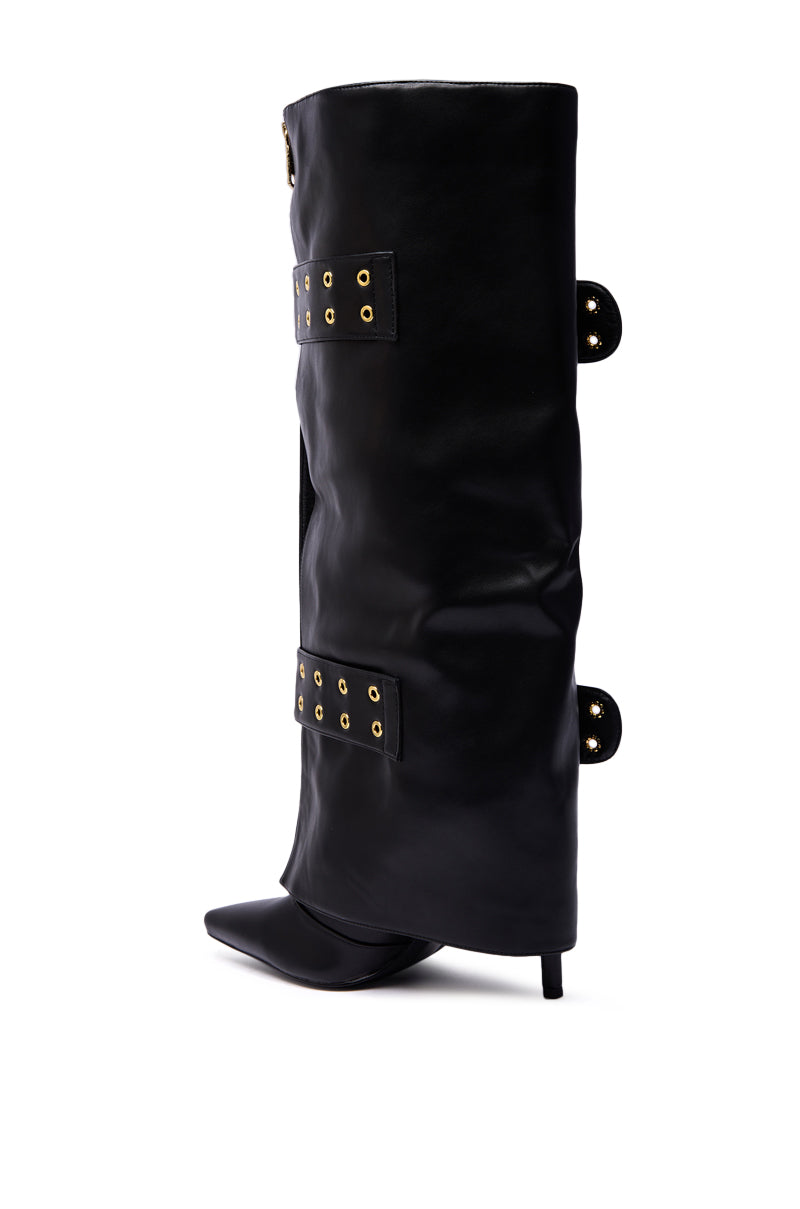 The AZALEA WANG ROOVER BLACK HARDWARE EMBELLISHED STILETTO BOOT is a tall black faux leather knee-high style with gold eyelet details, straps, a pointed toe, and thin stiletto heel, shown on a white background.