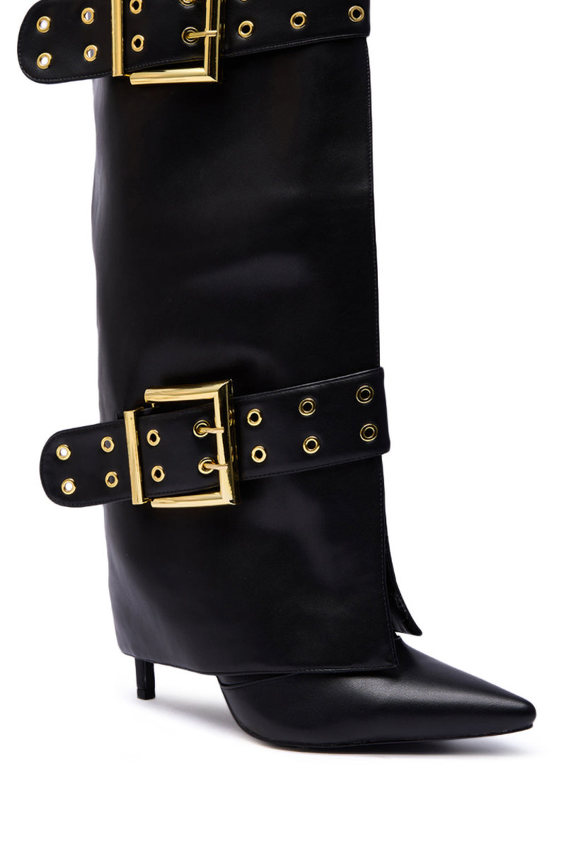 The AZALEA WANG ROOVER BLACK HARDWARE EMBELLISHED STILETTO BOOT is a knee-high black faux leather boot featuring a pointed toe, stiletto heel, and two large gold buckles with grommets as decorative straps.